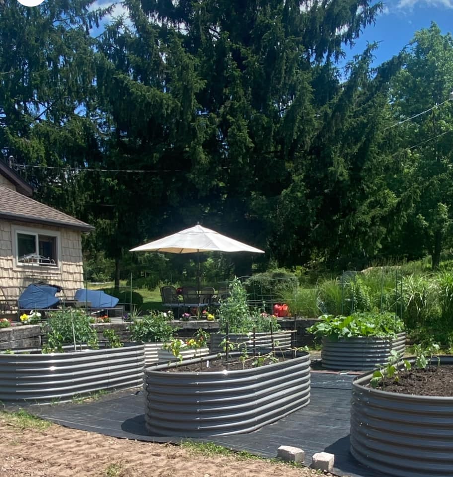 Garden with raised metal beds and outdoor furniture under a large umbrella.