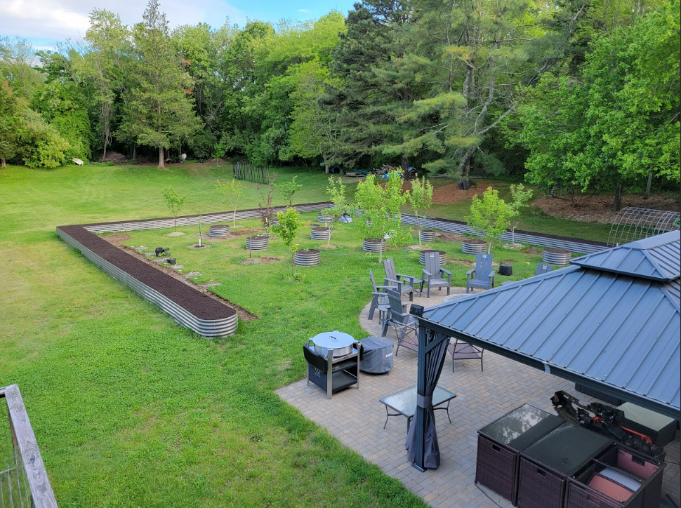 Outdoor area with green grass, trees, and patio furniture.
