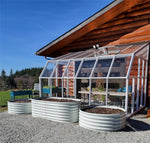 Greenhouse attached to a wooden cabin with outdoor furniture and plants. 