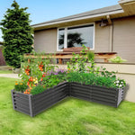 Gray raised garden bed with plants in front of a house