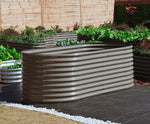 Corrugated metal planter with plants against a wooden fence 