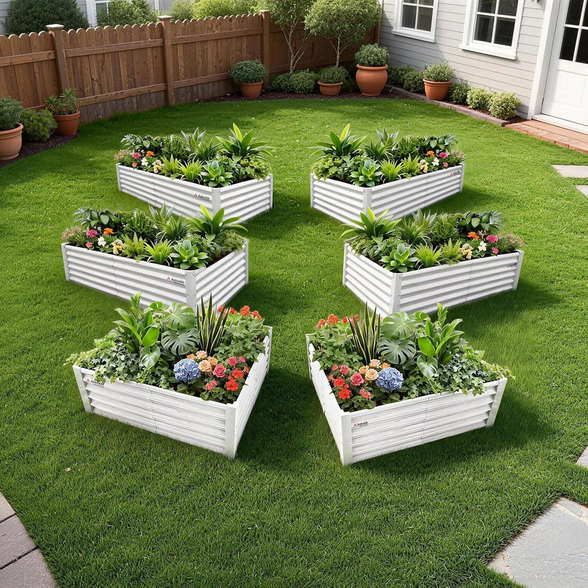 Set of white raised garden beds with plants and flowers on a grassy lawn. 